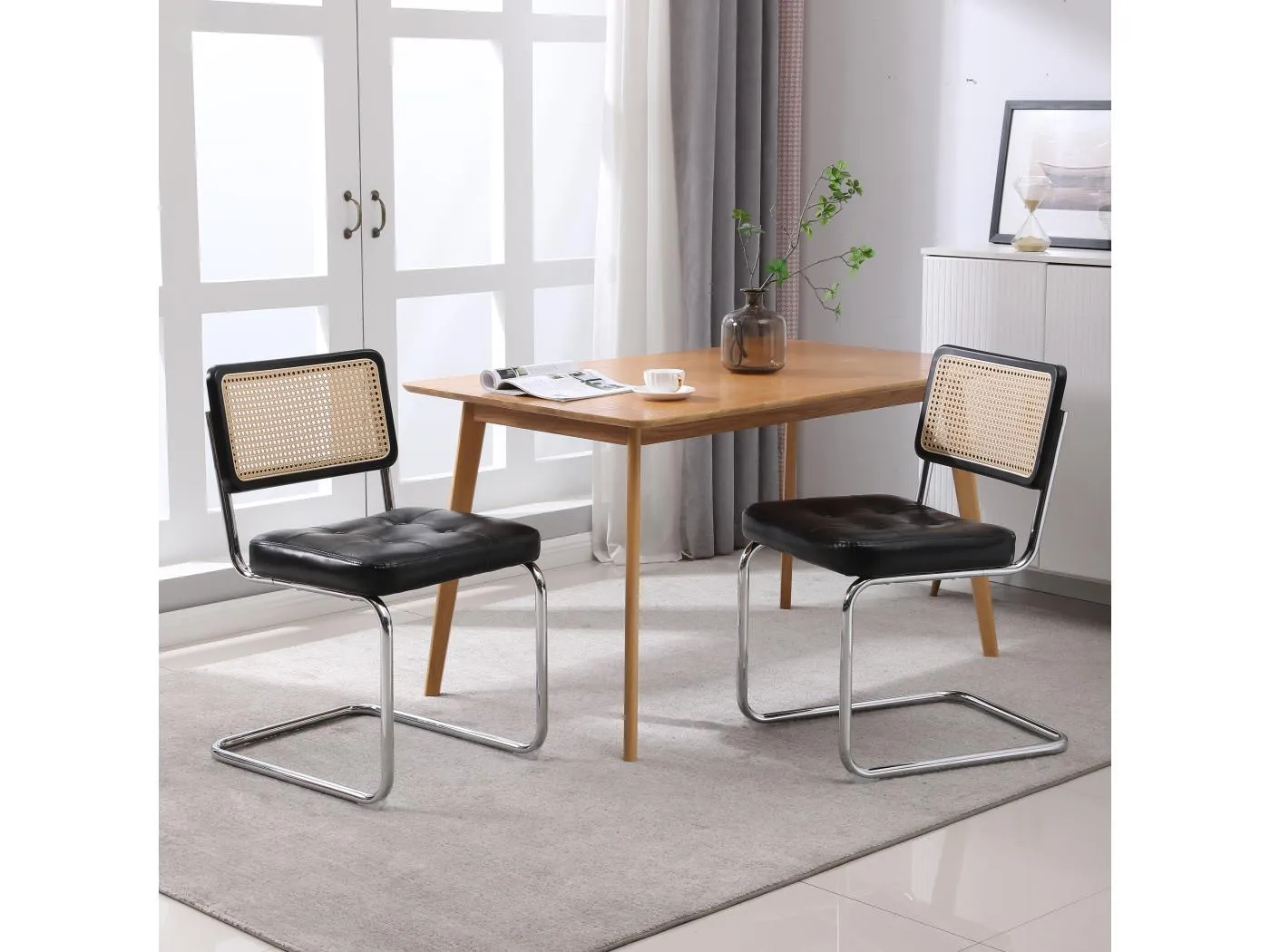 Ein Set aus zwei Esszimmerstühlen aus Rattan, mit weichen Kunstlederkissen, einer Rückenlehne aus Netzgewebe ohne Armlehnen, schwarz